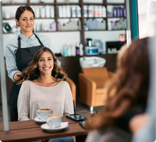 une coiffeuse et sa cliente contente devant le miroir