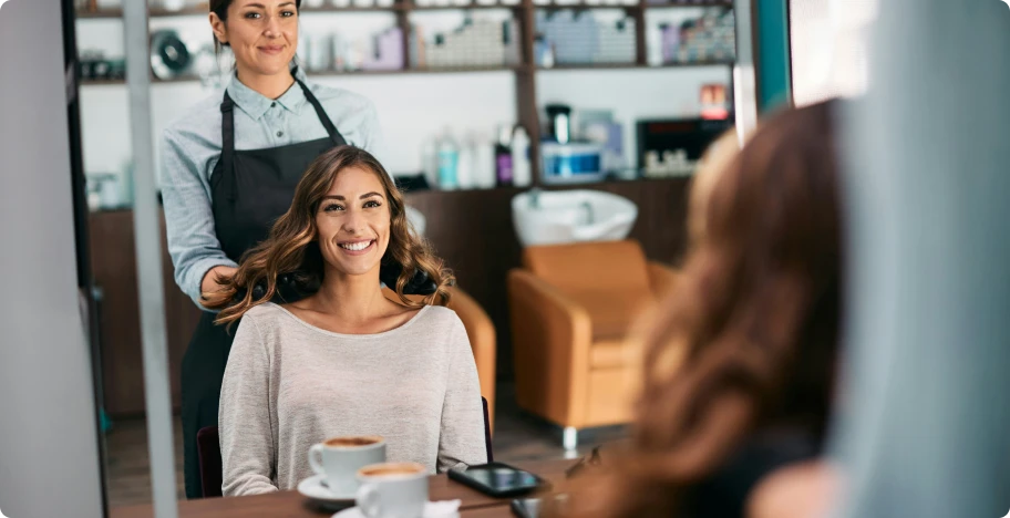 une coiffeuse et sa cliente contente devant le miroir