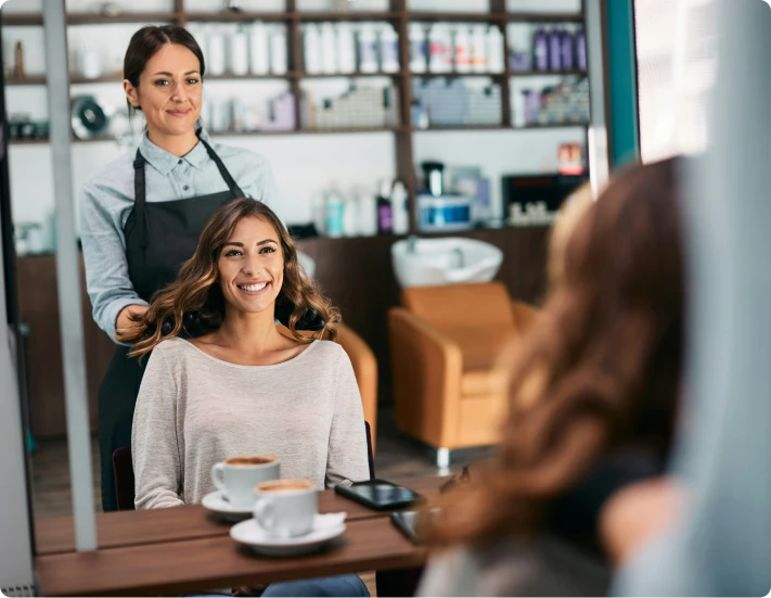 une coiffeuse et sa cliente contente devant le miroir