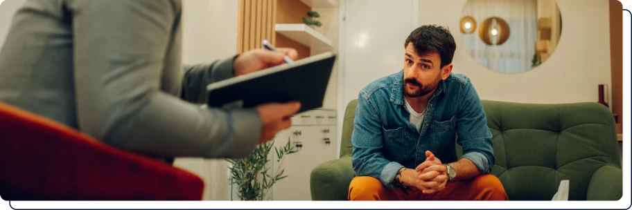 un homme qui écrit sur sa table avec un homme à ses côtés qui le regarde