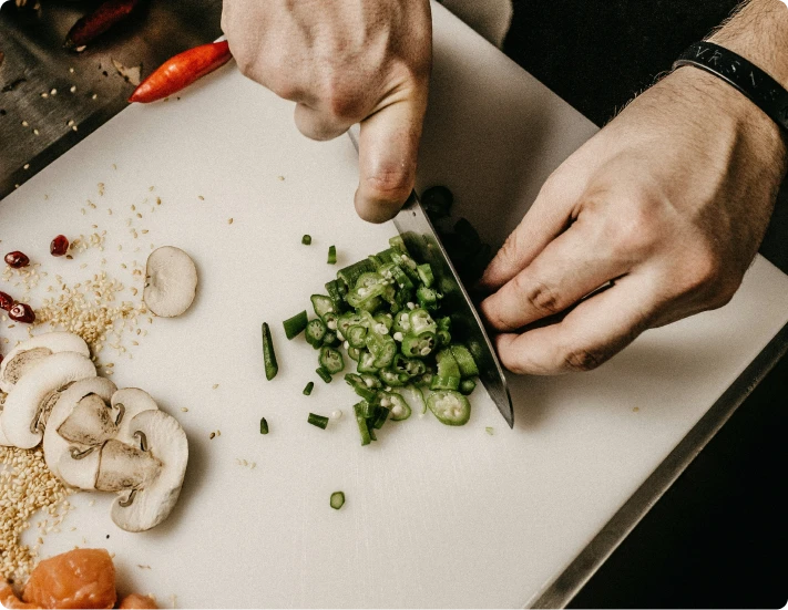 les mains d'un cuisiner qui coupe des légumes